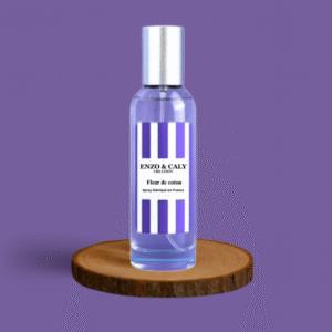 Spray au parfum d’ambiance Fleur de coton, présenté dans une bouteille en verre transparent avec une étiquette mauve et blanche, posé sur un rondin en bois avec un fond uni mauve – création élégante Enzo & Caly fabriquée en France.