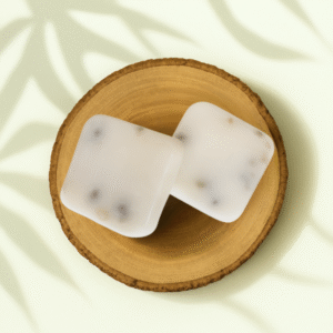 Deux fondants parfumés à la feuille de figuier, disposés en diagonale sur un rondin de bois, avec un fond crème et ombres de feuillage.