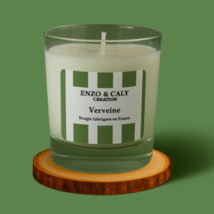 Bougie parfumée senteur Verveine, présentée dans un verre transparent avec étiquette verte et blanche, posée sur un rondin en bois et sur un fond uni vert – création élégante Enzo & Caly fabriquée en France.
