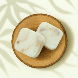 Deux fondants parfumés carrés à effet marbré beige et violet clair, présentés sur un support en bois naturel.