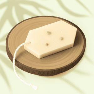 Tablette parfumée au monoï , de forme hexagonale, de couleur ivoire, avec trois petits boutons floraux incrustés, et une cordelette blanche, placée sur un socle en bois sous une lumière douce