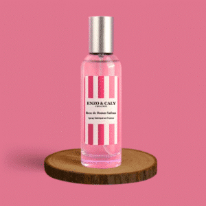 Spray au parfum d’ambiance Rose Damas safran, présenté dans une bouteille en verre transparent avec une étiquette rose et blanche, posé sur un rondin en bois avec un fond uni rose – création élégante Enzo & Caly fabriquée en France.