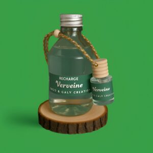 Ensemble composé d’un mini diffuseur de parfum d'ambiance Verveine et de sa recharge, présentés respectivement dans un petit flacon et dans une bouteille en verre transparent, avec une étiquette verte, posés sur un rondin en bois avec un fond uni vert – création élégante Enzo & Caly fabriquée en France.